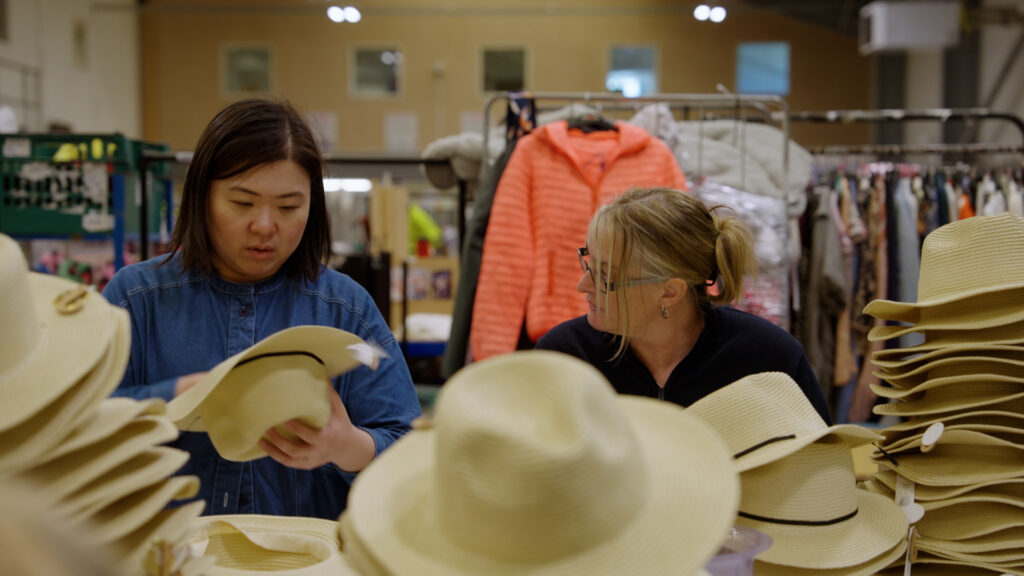 This picture shows two women pricing hats in the Newlife warehouse