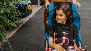 Picture shows a child being pushed in a buggy supplied by Newlife