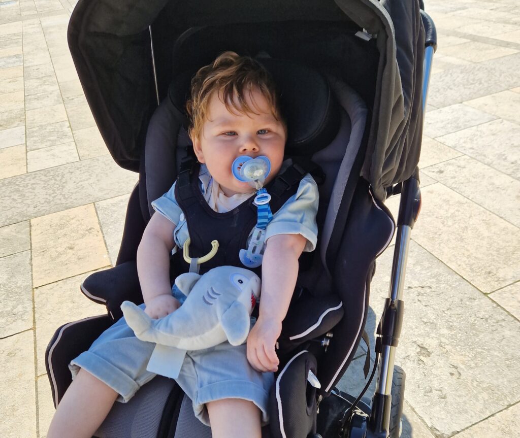 Picture shows a child in a buggy supplied by Newlife holding a soft toy shark.
