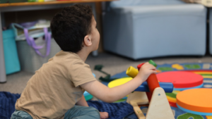 This image shows a boy playing on the carpet with sensory toys.