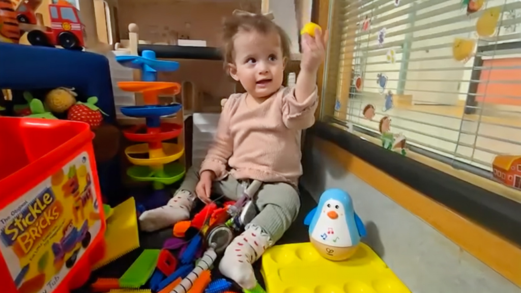 Image shows a young girl sitting playing with toys.