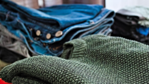 Image shows jumpers and jeans piled up on a table
