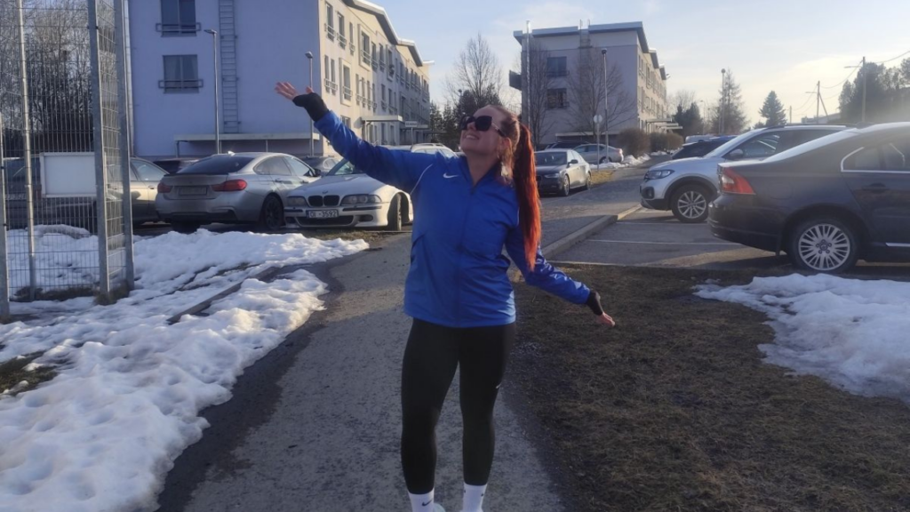Image shows lady throwing her arms out whilst on a snowy pavement