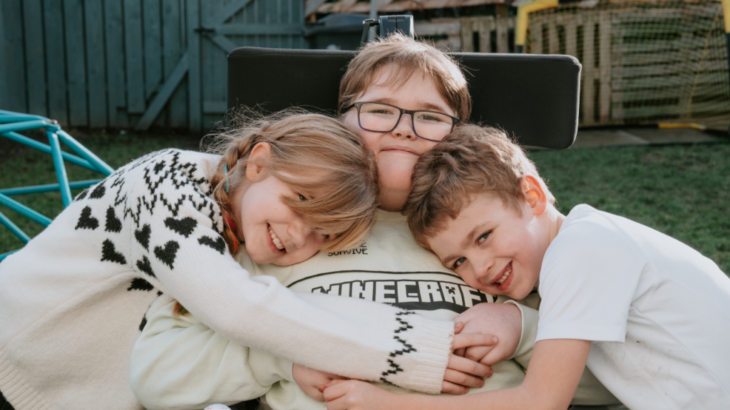 Image shows three siblings cuddling