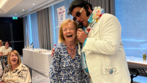 Image is of an Elvis impersonator putting his arm around Newlife fundraiser Pam Ling.