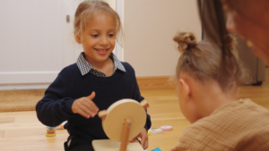 Two children playing with a wooden sensory toy.